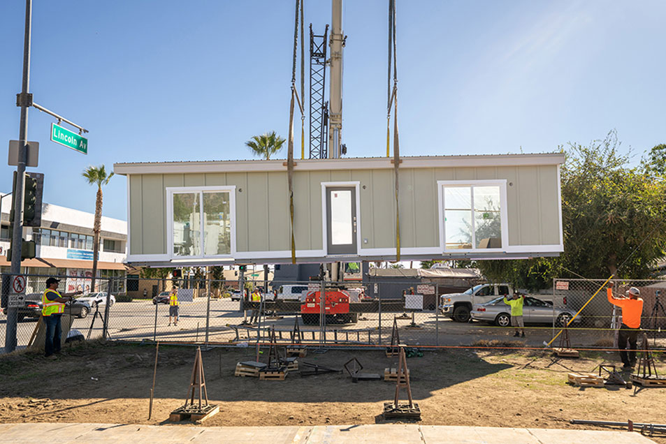 A prefab house gets lowered to the ground